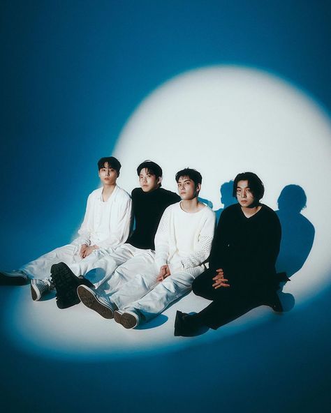 This  contain an image of  BTOB  sitting on the ground in front of a blue background, with one man's shadow behind them