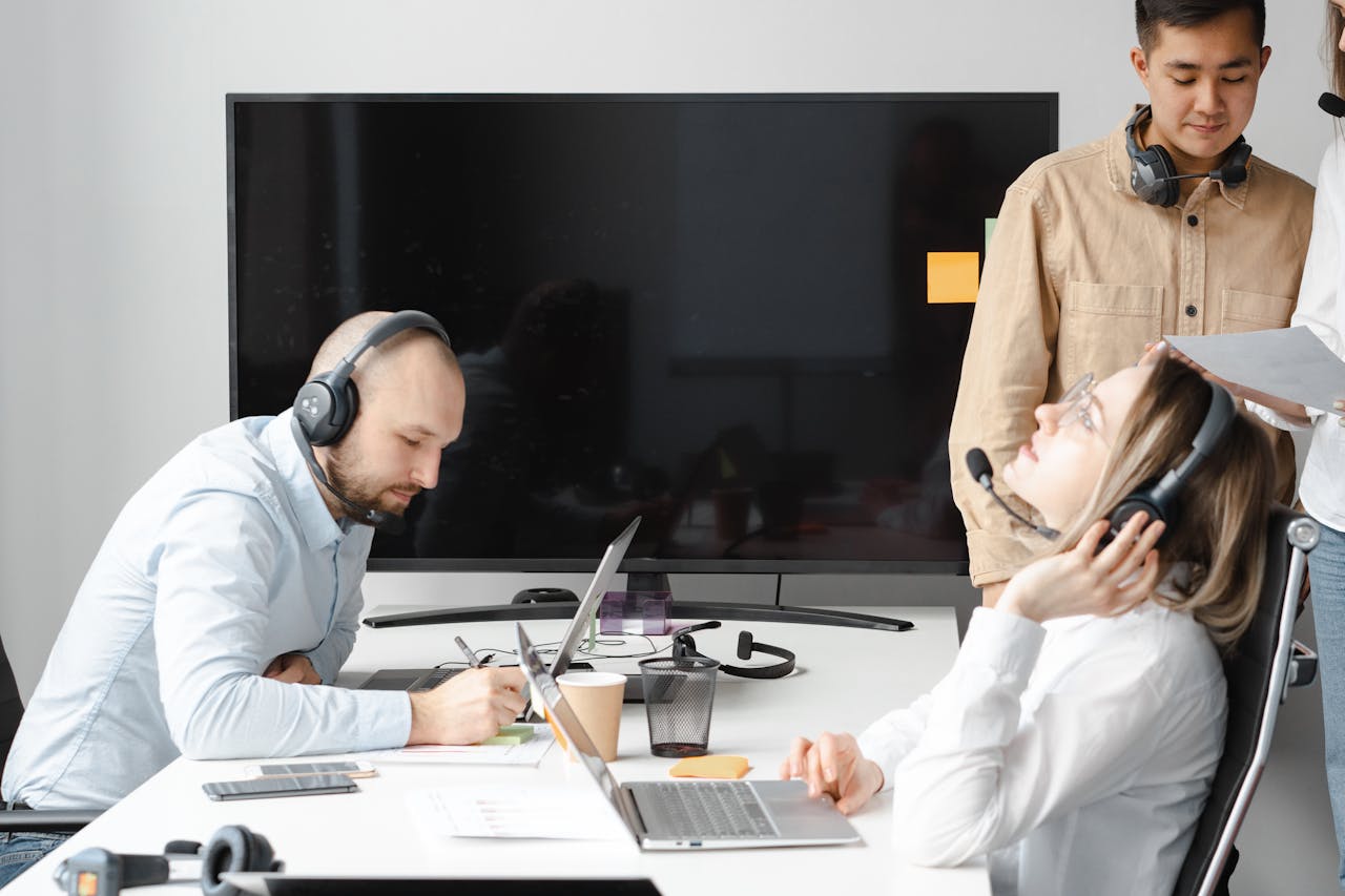 A diverse team of professionals working at a desk with headphones on.