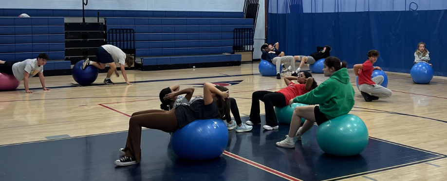 image of students in the gym sitting on bouncy balls