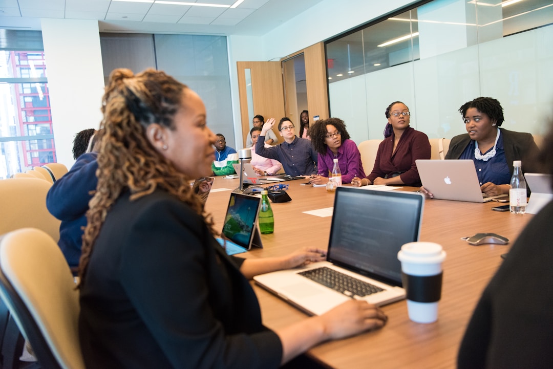 Professionals in an office gathered around a table with laptops, leveraging call data to optimize marketing strategies using telephony software