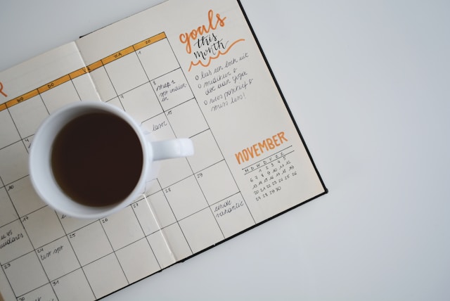 A cup of coffee sitting on top of a  goal-setting calendar