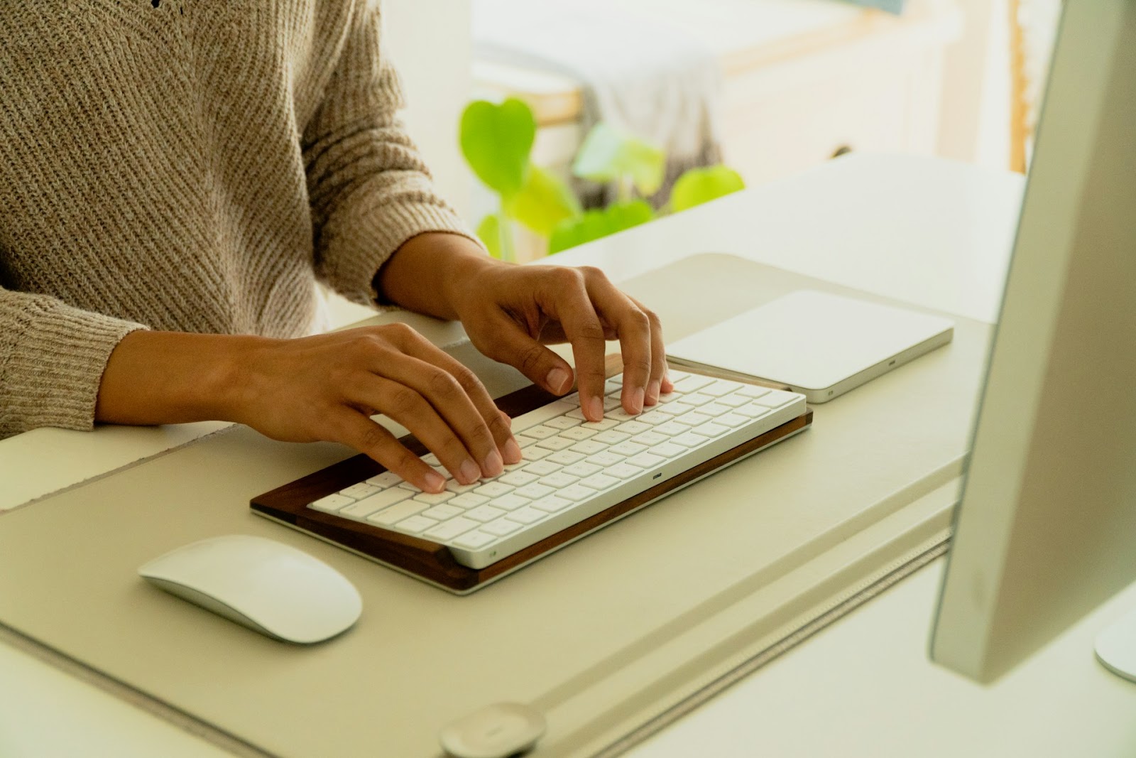 An aesthetic shot of a female business owner working at her desk on a Mac computer