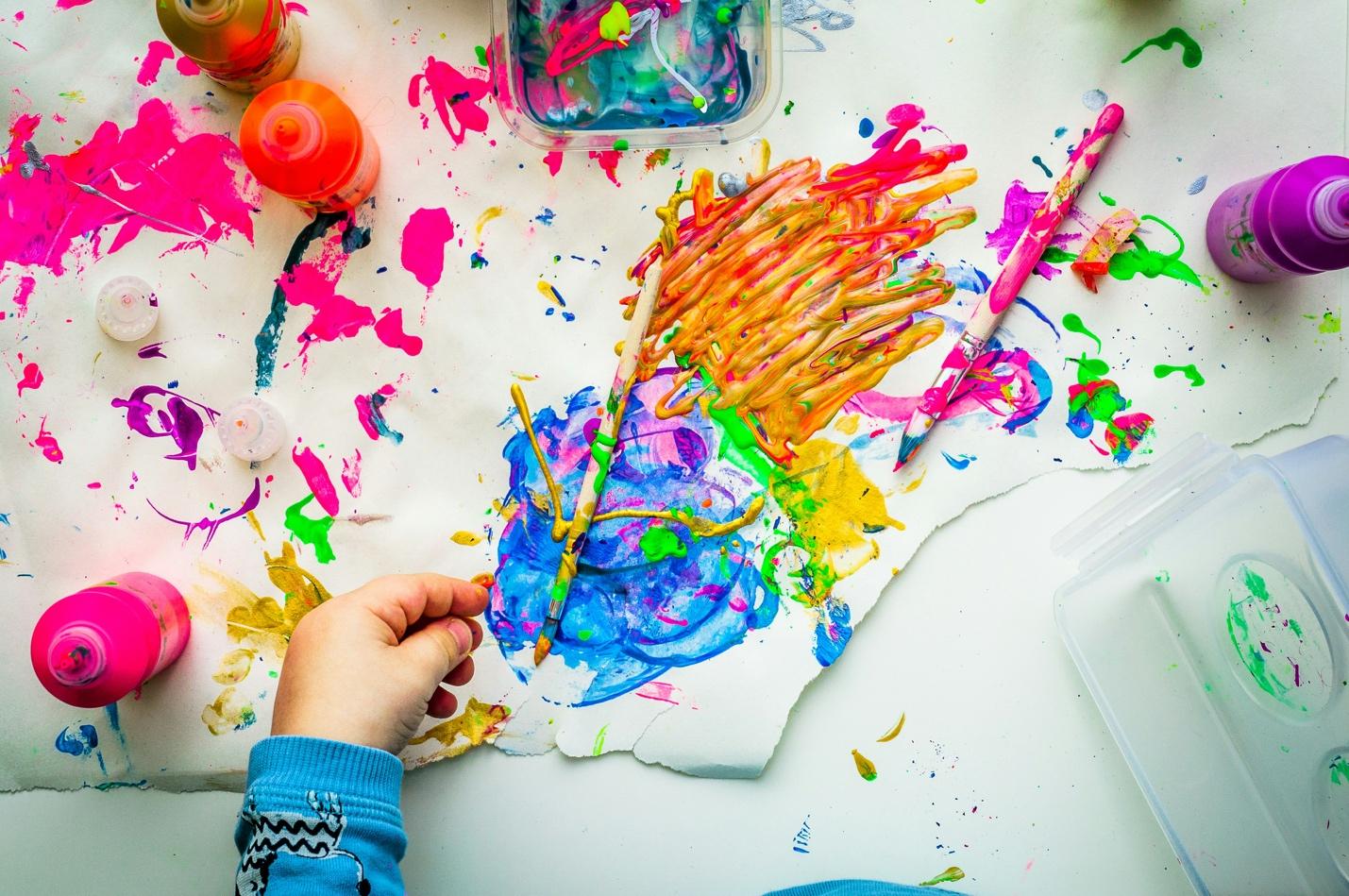 A child painting with paintbrushes and brushes

Description automatically generated