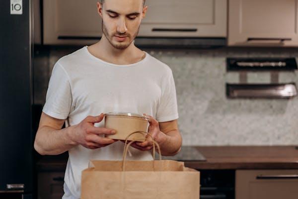 A man holding a biodegradable wooden or recycled paper food container