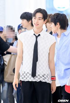 This contains an image of RIIZE Seunghan wearing a white sleeveless shirt with a necktie and a black trouser