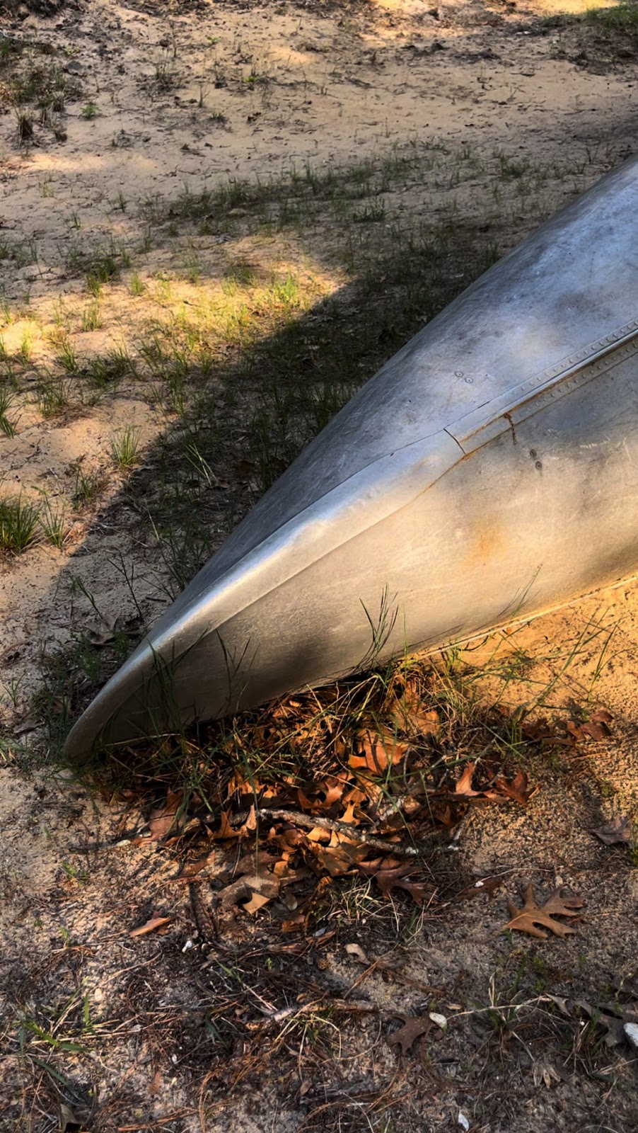 Old canoe laying in dirt with sunlight.