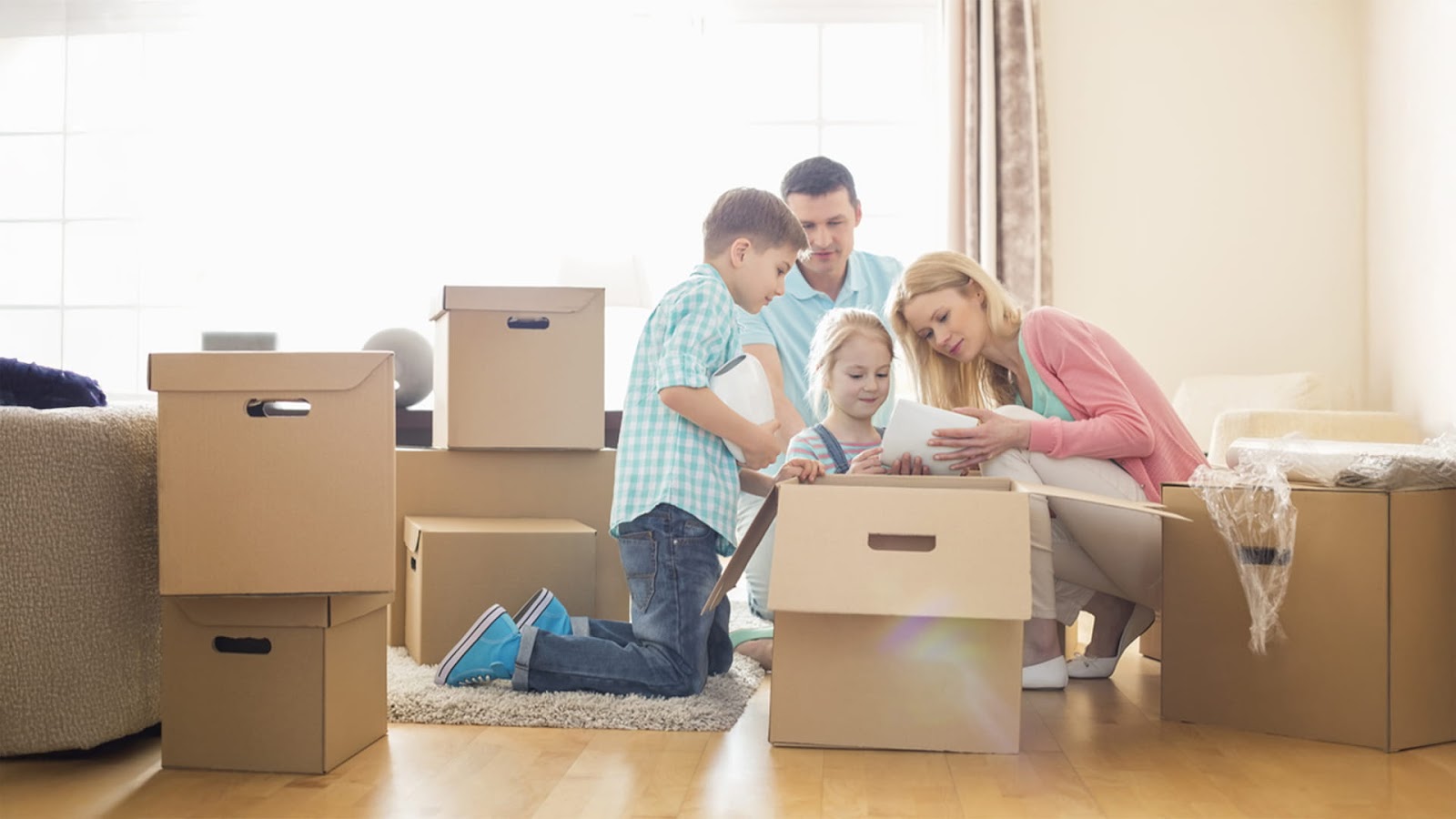  A family is sorting through cardboard boxes in a bright living room, staying organised and enjoying their time together while packing for a last-minute move.