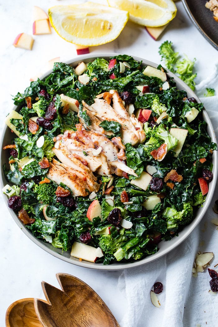 A photo of a kale salad loaded with apples, bacon, cranberries and smoked chicken.