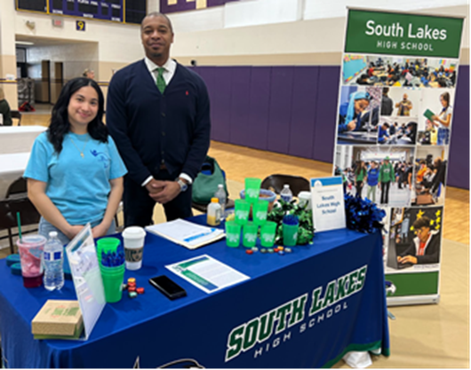 High School student with South Lakes principal at a recruiting table at the FCPS Instructional Job Fair. 