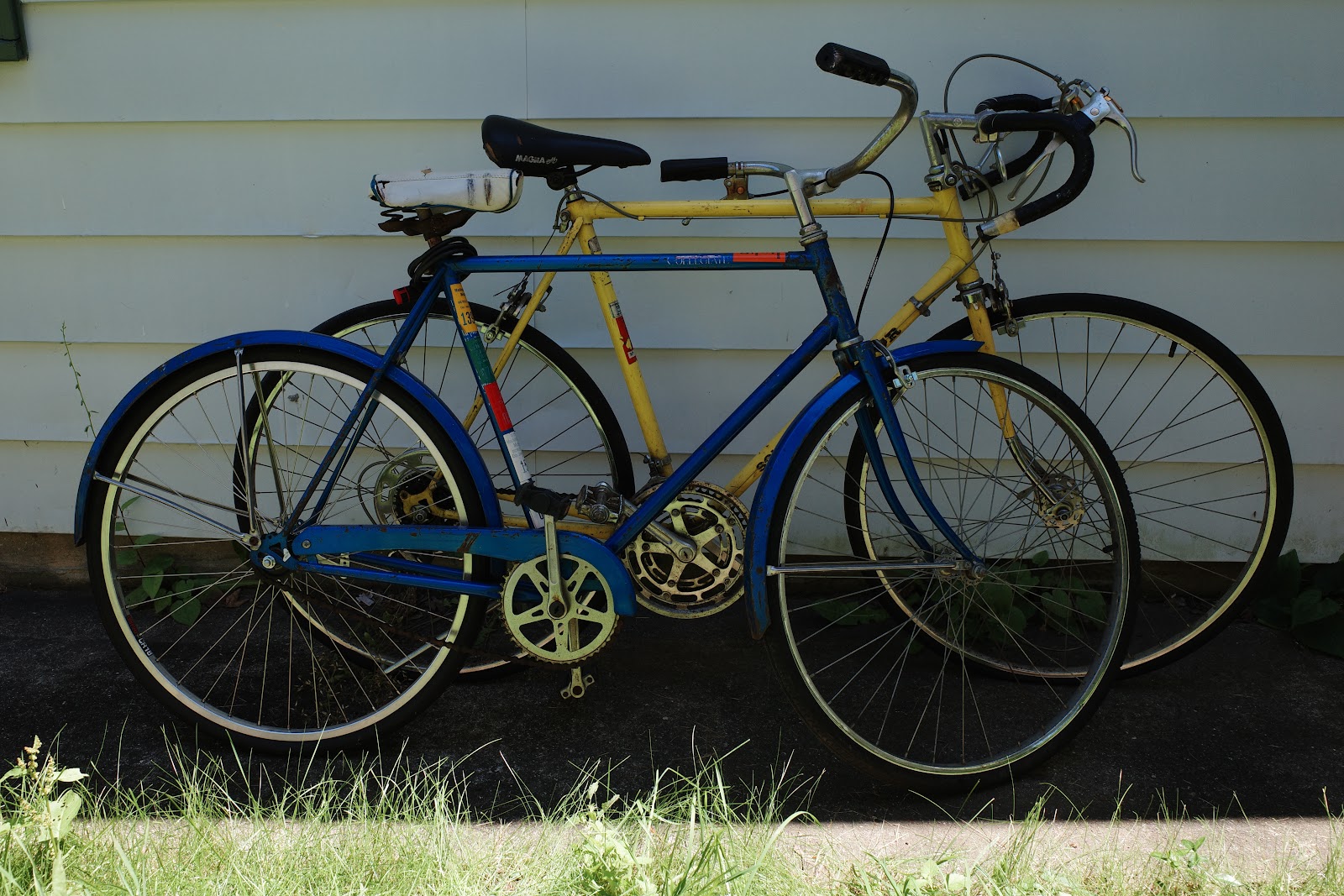 Old bikes leaning against a house.
