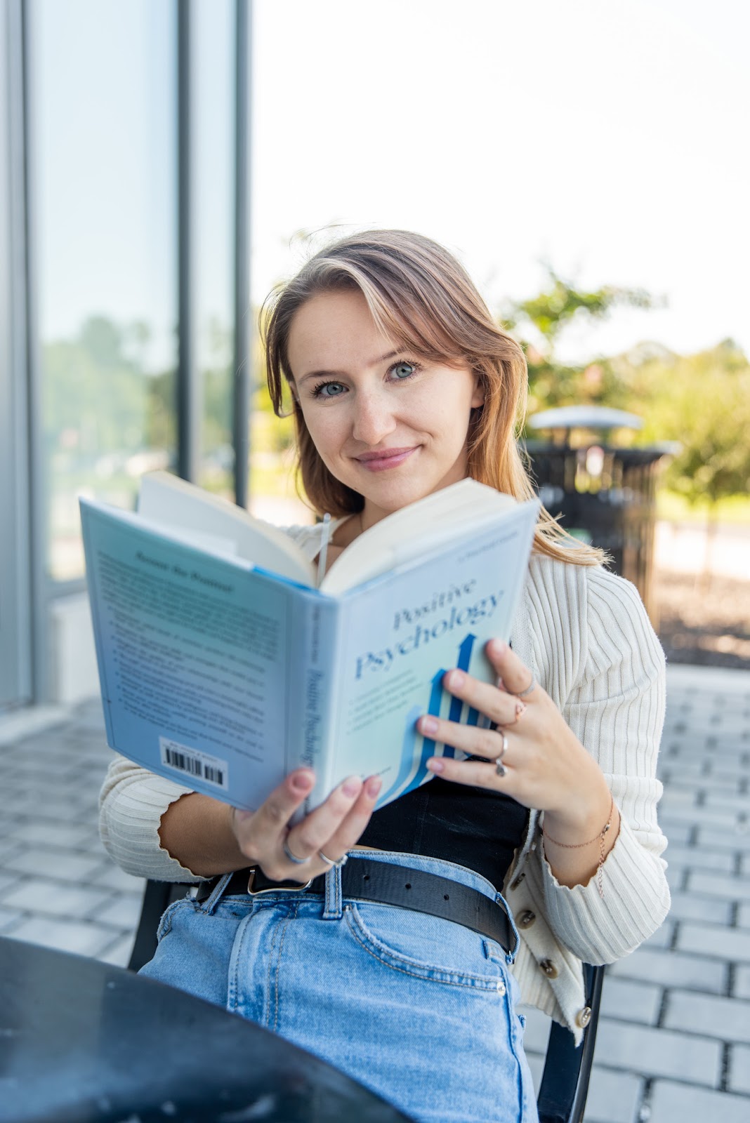 Student studying for an online psychology degree with a positive psychology book outside