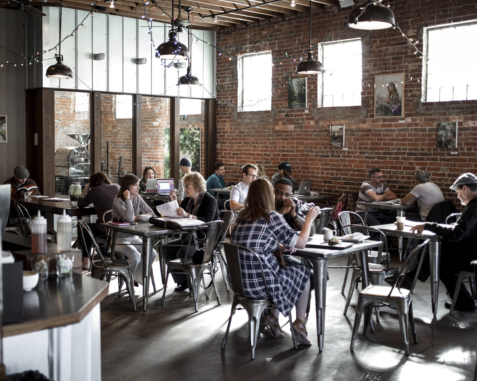 Photo of interior of a cafe with brick walls and people sitting at tables. Photo via Pexels