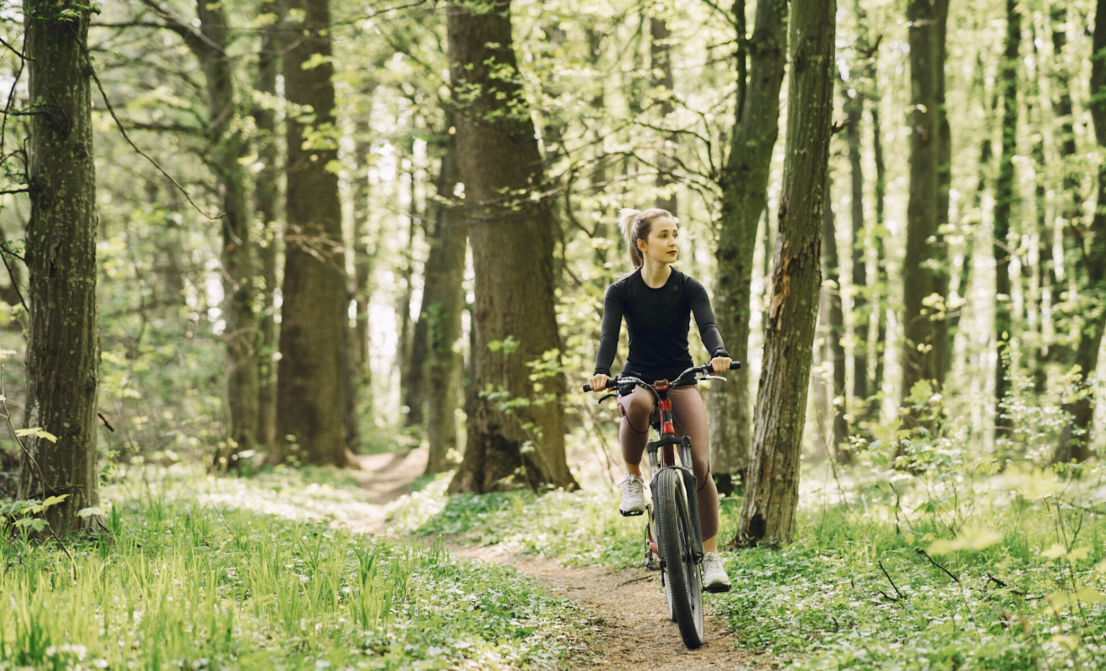 Une femme à vélo en forêt lors de son week-end cyclotourisme