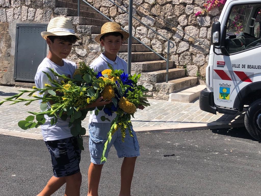 Two boys carrying flowers in front of a van

Description automatically generated