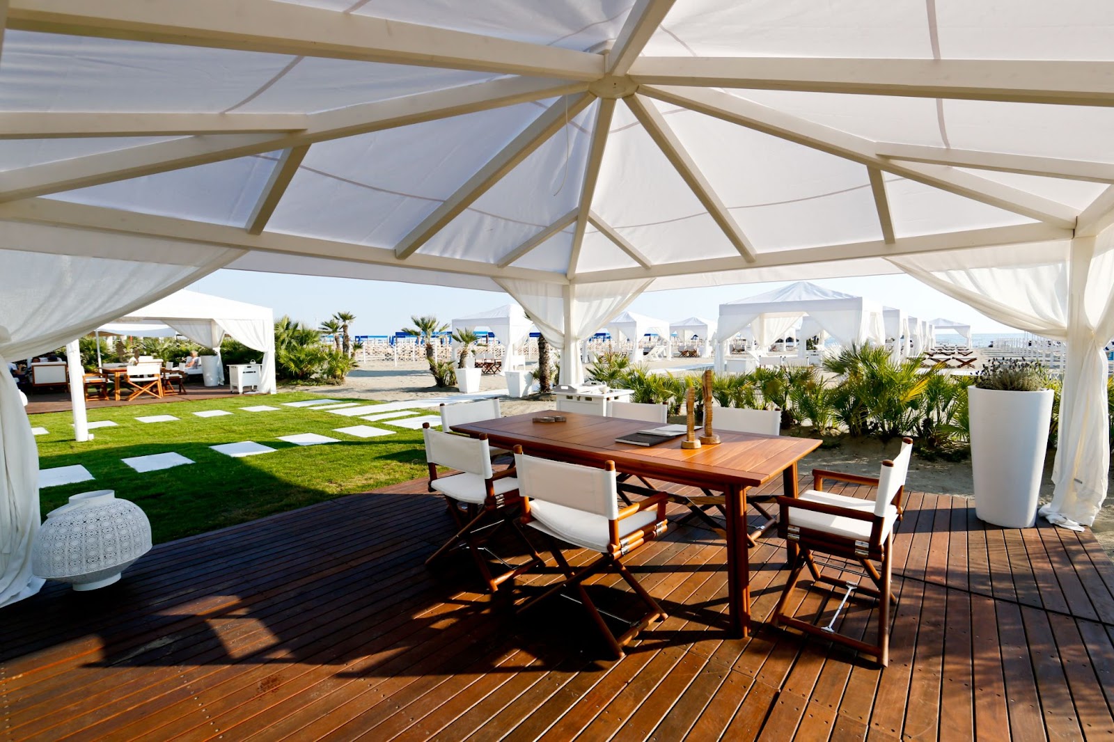 A stunning private beach at La Datcha Forte dei Marmi featuring a decked shoreline, ten individually designed cabanas, an alfresco restaurant, and an outdoor pool, offering a luxurious and secluded retreat.