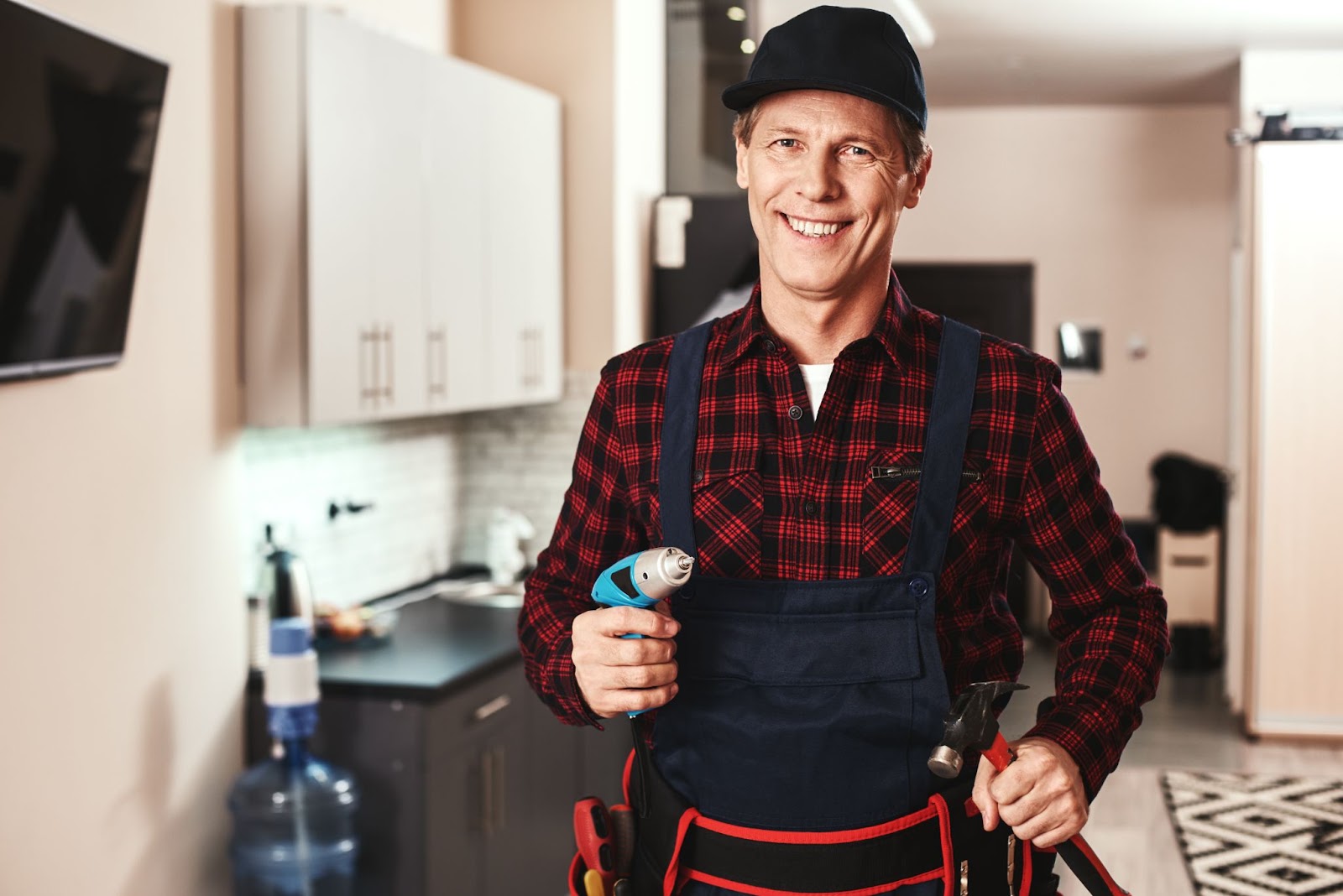 Smiling plumber holding tools in his hands. 