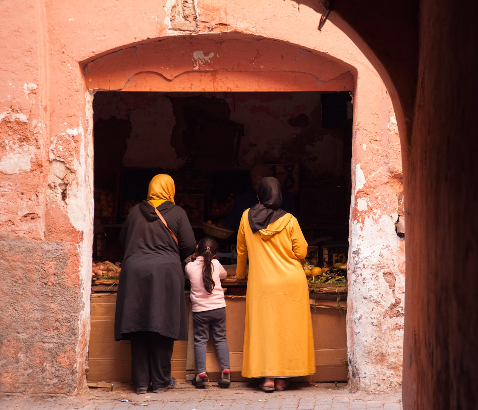 Women wearing coat and orange Abaya in a souk - (Credits Unsplash)