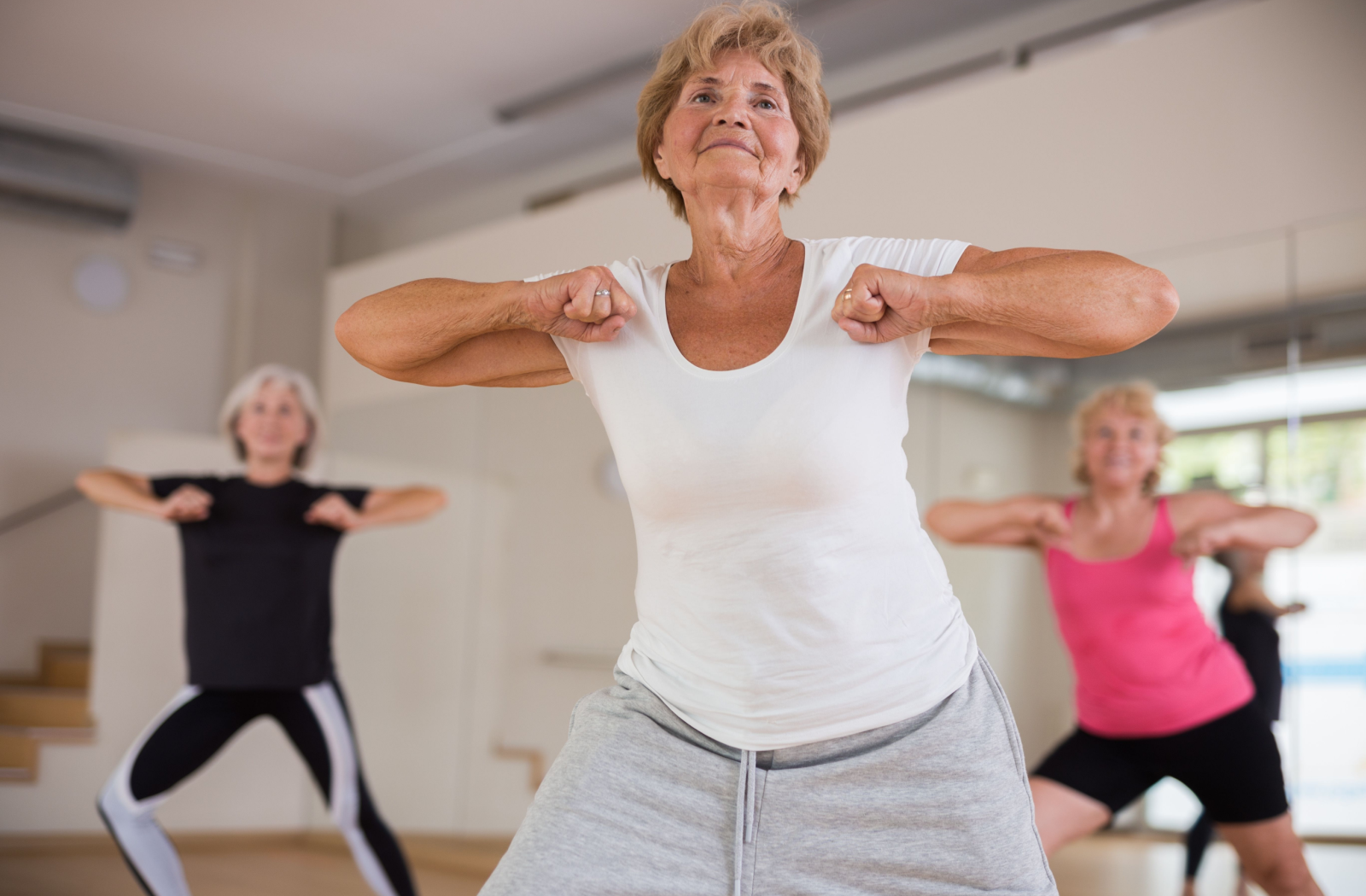 3 seniors in activewear participate in a dance fitness class.