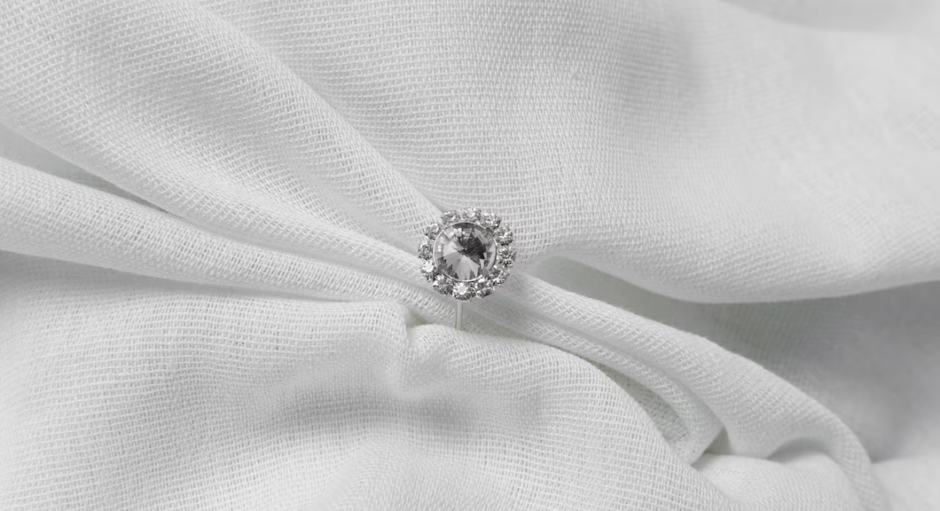 A diamond ring on a white clothDescription automatically generated