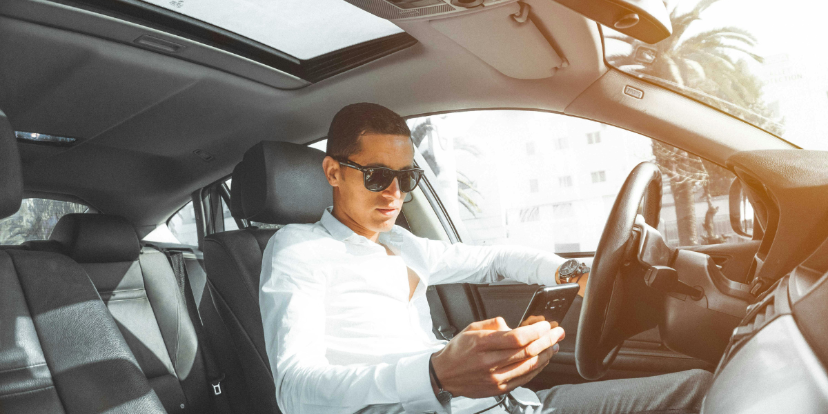 A man in his rental car checking his phone.