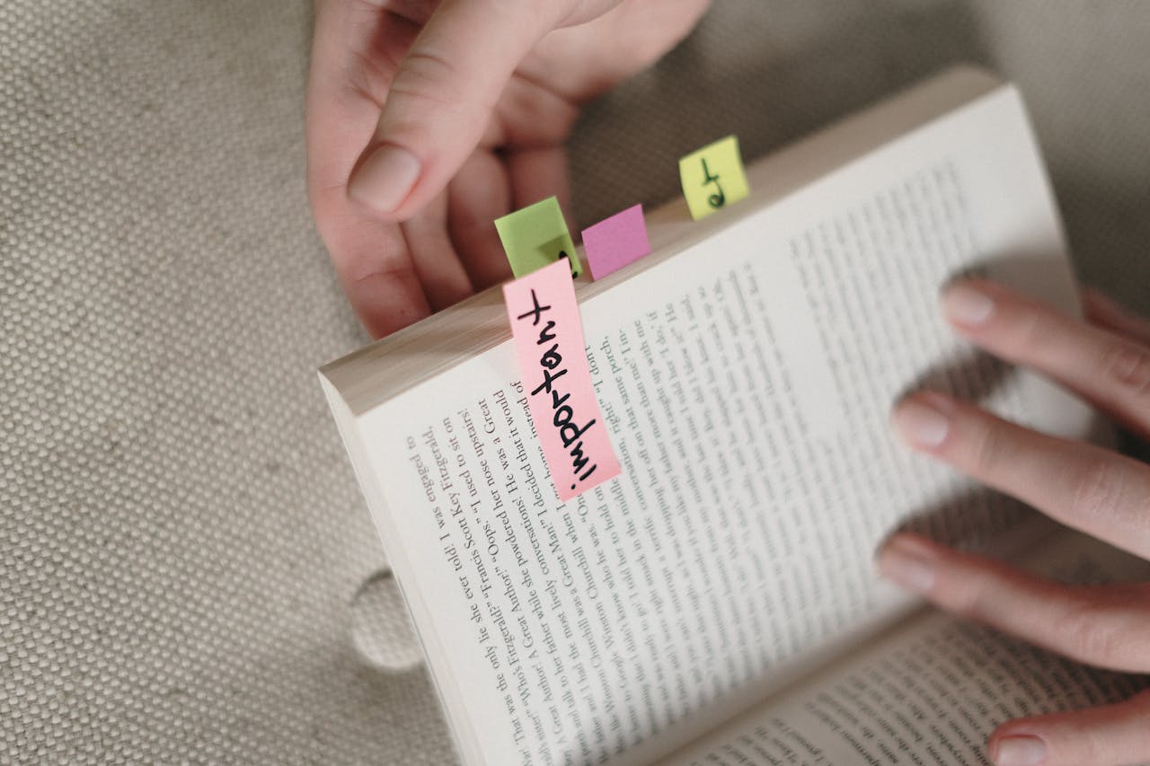 A person holds a book with colorful sticky notes.