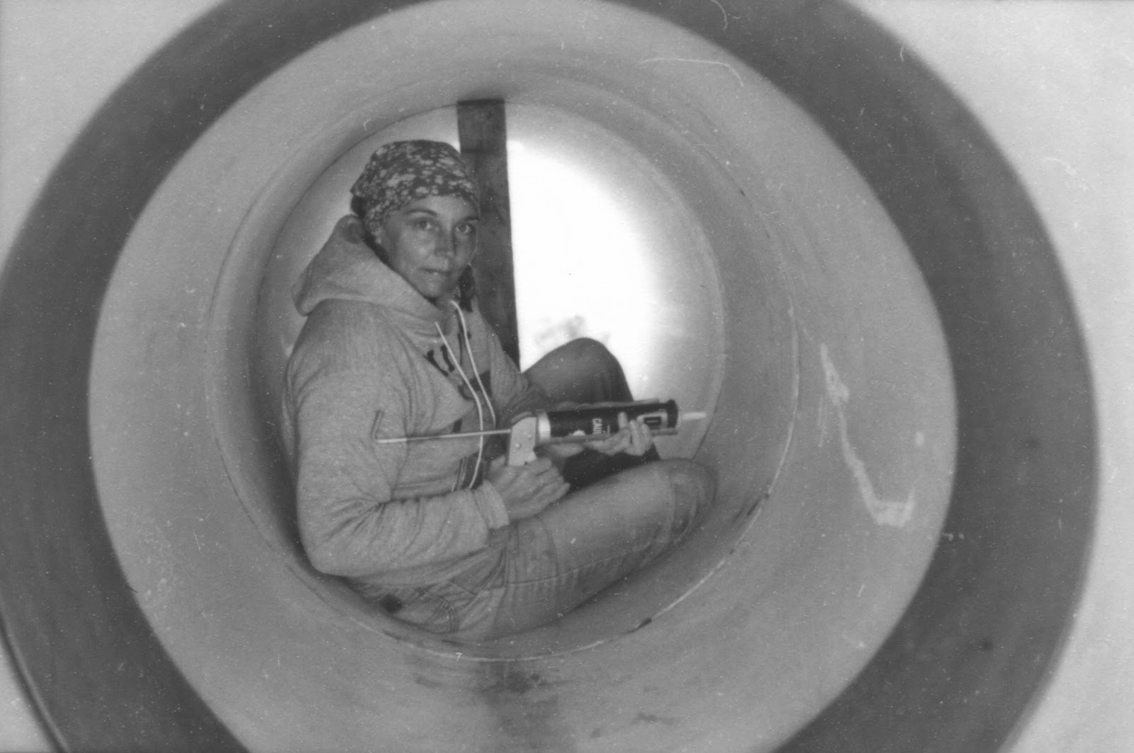 Image of the artist - Nancy Holt during the construction of Star-Crossed inside the pipe with a caulking gun.