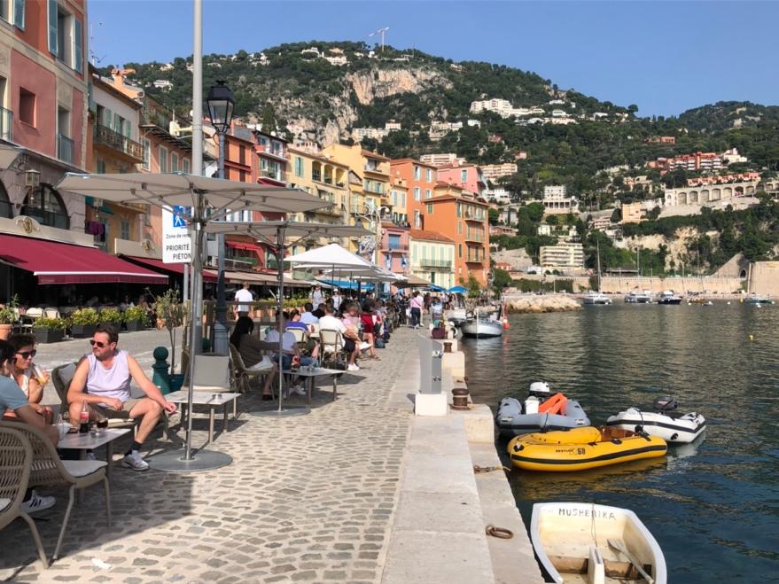 A group of people sitting on a sidewalk next to a body of water

Description automatically generated