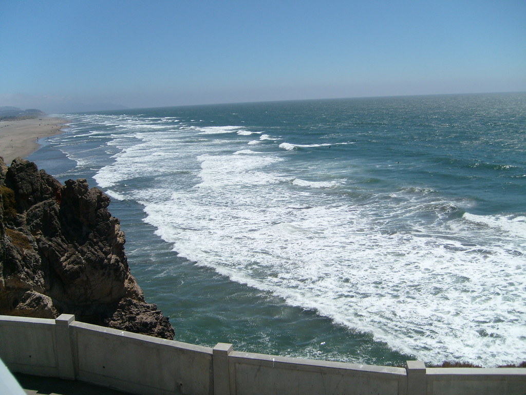 Clean and clear water  and brown sand on the beach and large rock at the shore of beach