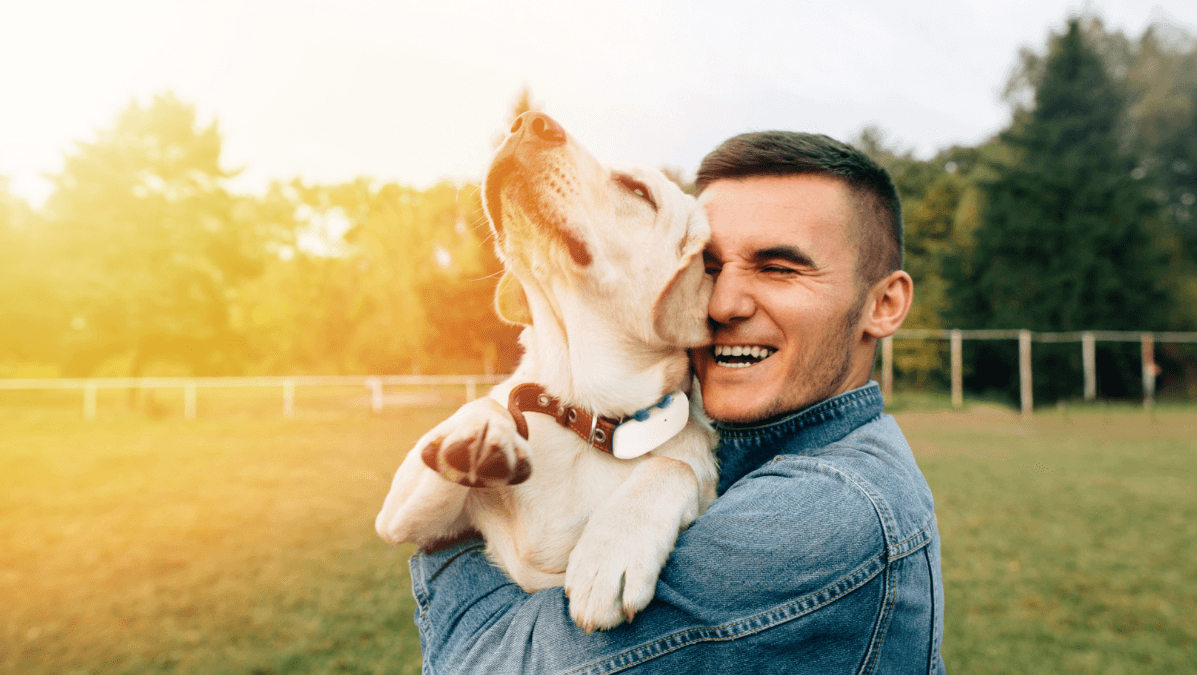 Un homme prend dans ses bras son chien qui porte un collier GPS Tractive