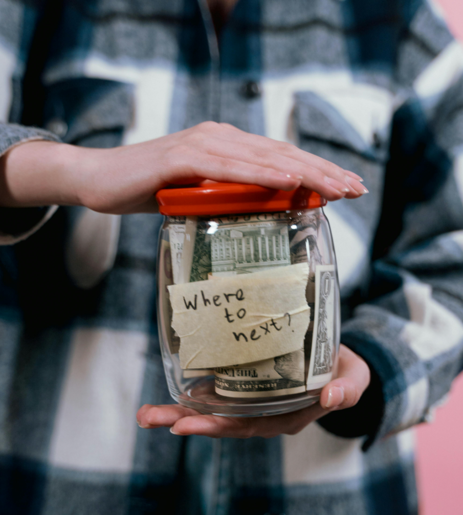 A person holding a jar of money

Description automatically generated