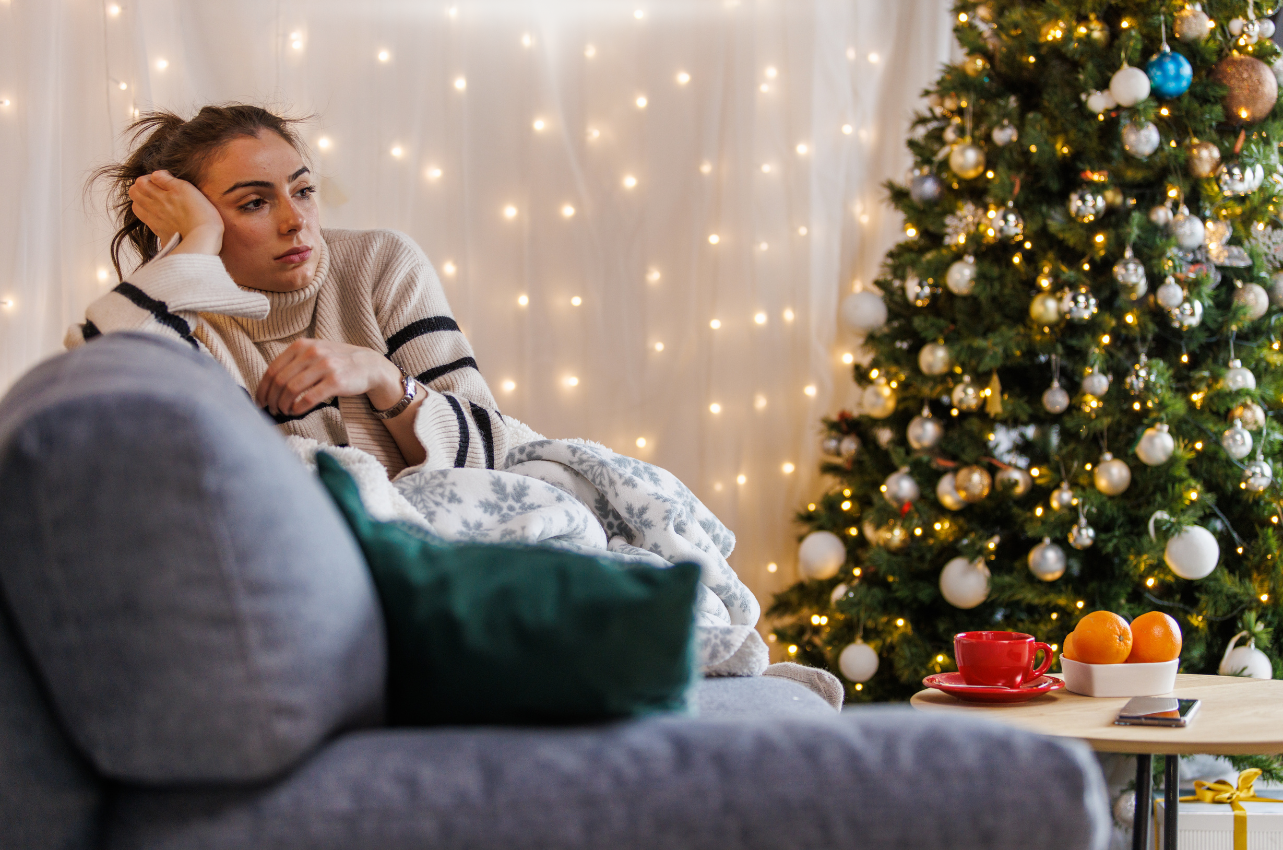 Woman sitting on coach surrounded by Christmas decorations // Healthier Veterans Today