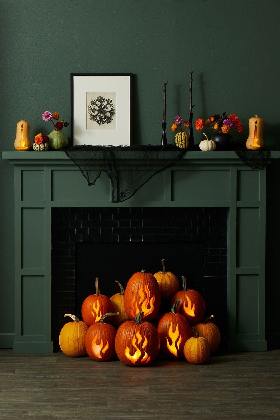 diy halloween decorations, pumpkins carved with flame designs by the fireplace