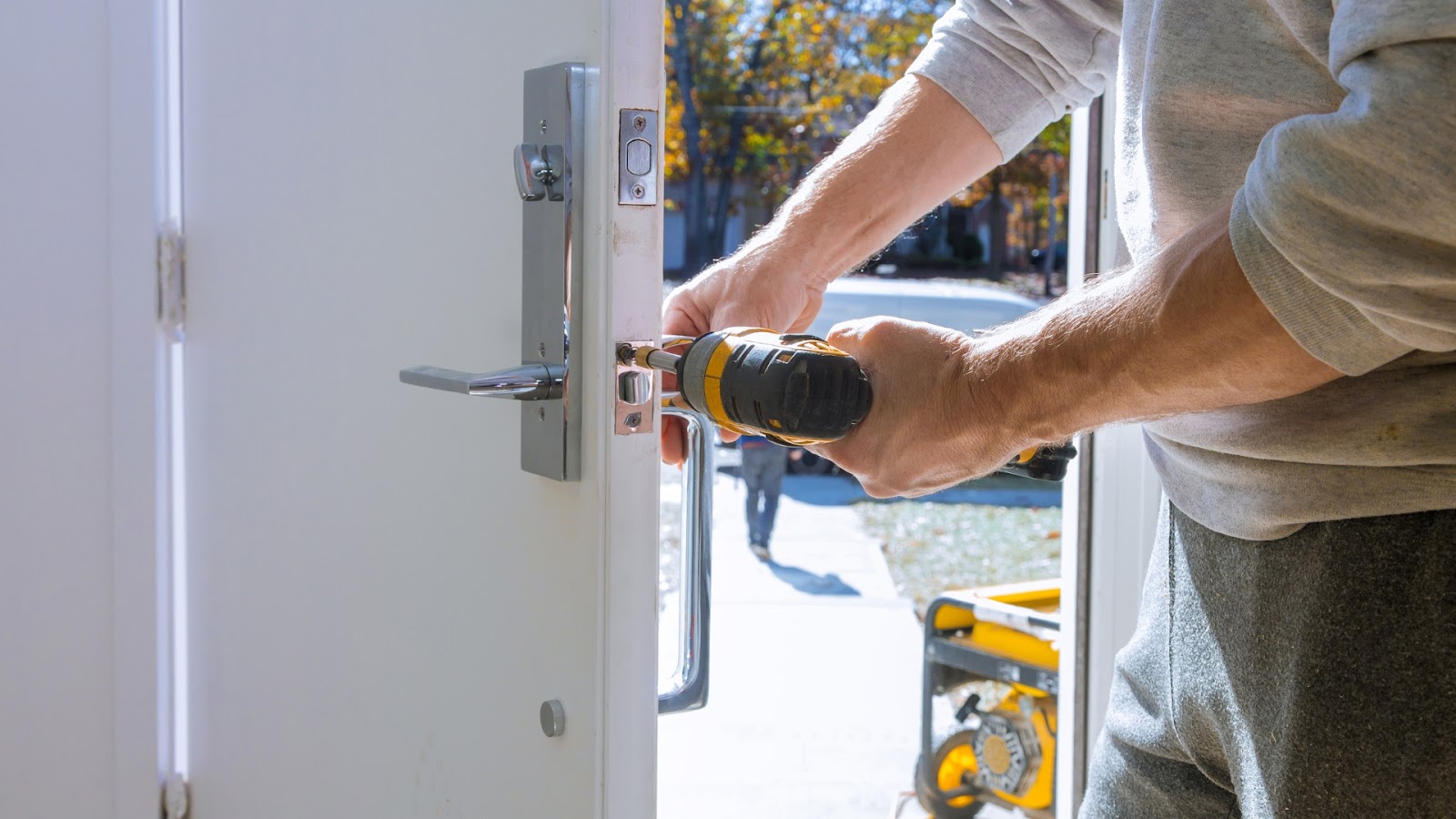 Technician installing a lock for the main door using a drill.