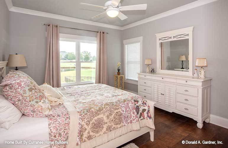This bedroom has gray walls, a white bed, and a matching dresser topped with a framed mirror.