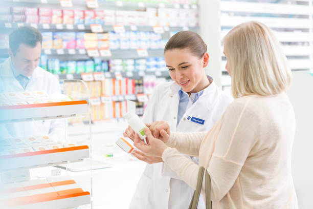 A friendly pharmacist in a white coat discussing the best supplements for pain and inflammation with a customer.