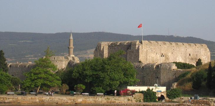 A stone castle with a flag on top

Description automatically generated