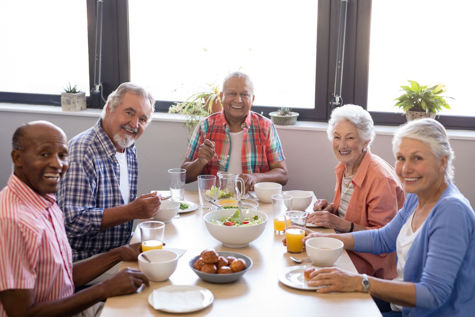 A group of seniors smiling while enjoying breakfast together.