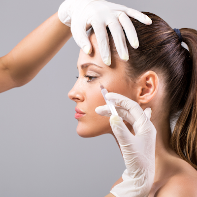 Woman sitting comfortably during a skin procedure, with a professional performing treatment using specialized equipment, showcasing a relaxing and professional skincare experience.