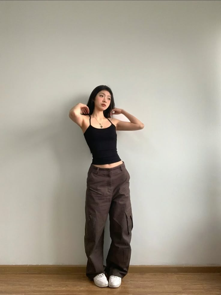 seorang wanita memakai celana cargo cokelat dan tank top hitam