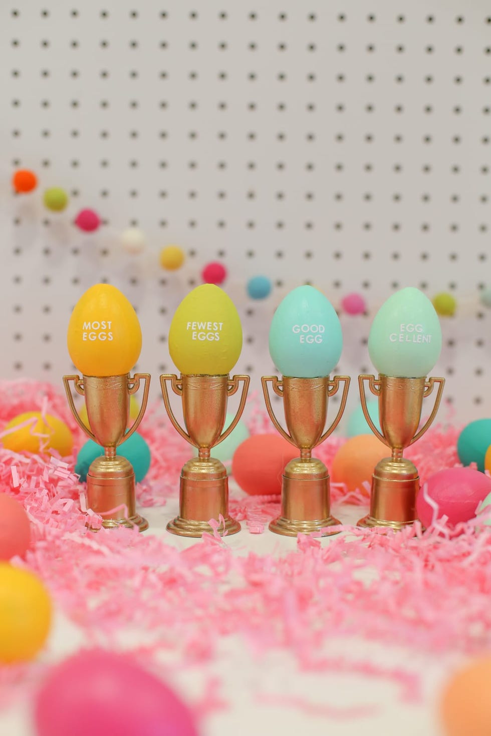 easter egg hunt ideas, colorful eggs on top of small gold trophies