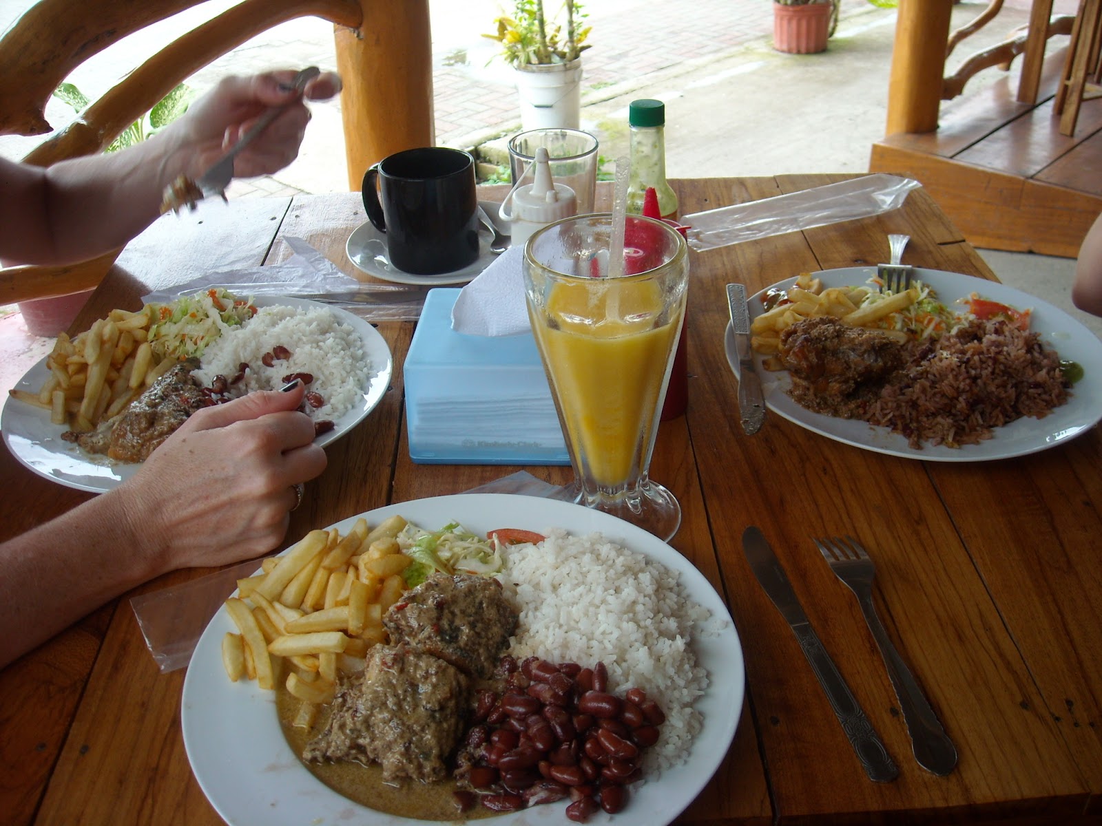 Hand holding food while people enjoy their meal on the beach at Playa Hermosa.