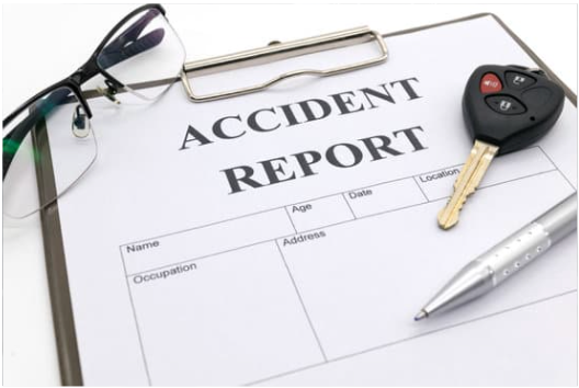 car accident report form on a clipboard with car keys on it and a pen