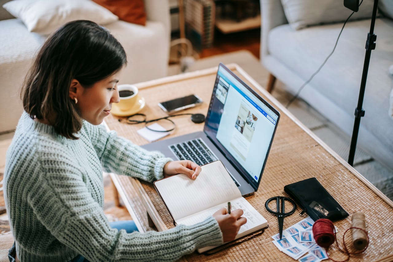 A woman focused on her laptop, surrounded by a cozy home office setup, working diligently on her tasks.