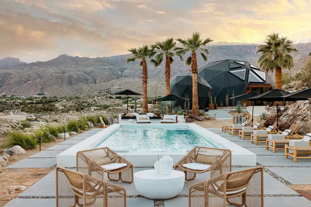 pool in palm desert california with a dome shaped airbnb lounge chairs and views of mountains and palm trees