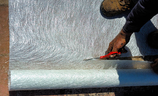 Worker cuts fiberglass duct board with scissors.