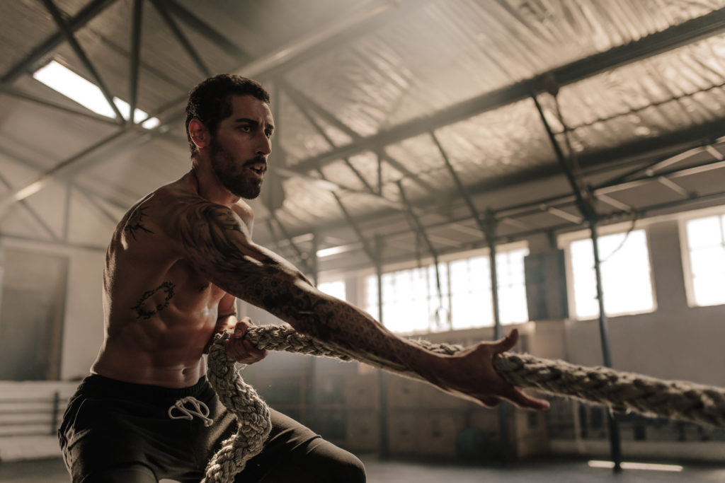 Jeune homme qui tire une corde au crossfit