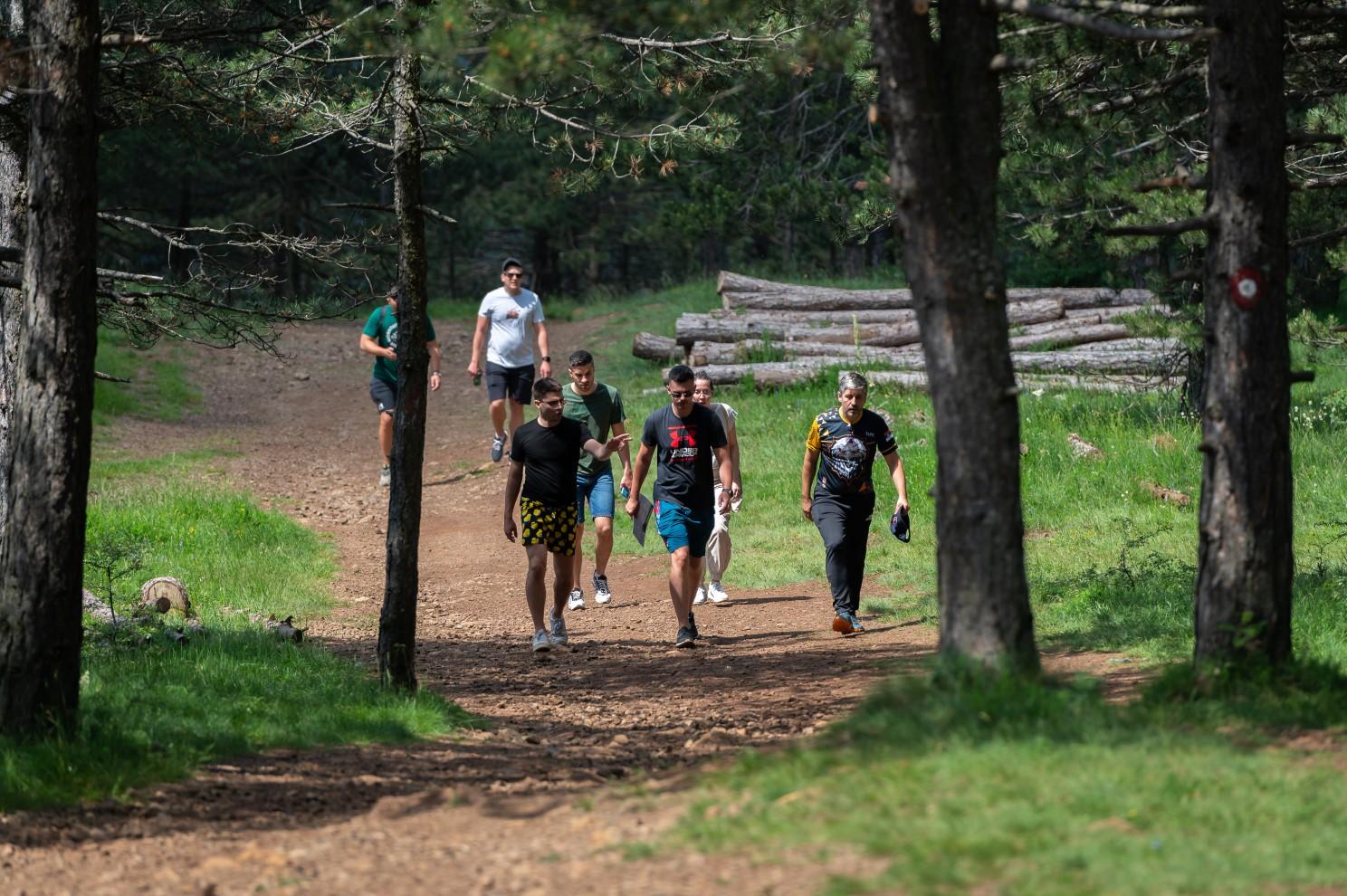 A group of people walking on a dirt path

Description automatically generated