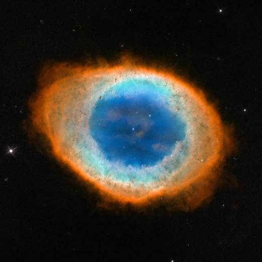 Black background holding an oval of light. The outer ring of the oval is orange-red. Moving inward the ring is more greenish-yellow. The center of the ring is bright blue with one small star at its center and another above and to the right of it.