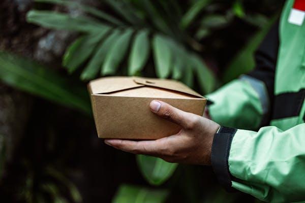 A biodegradable food packaging container made of paperboard or other paper-based materials.