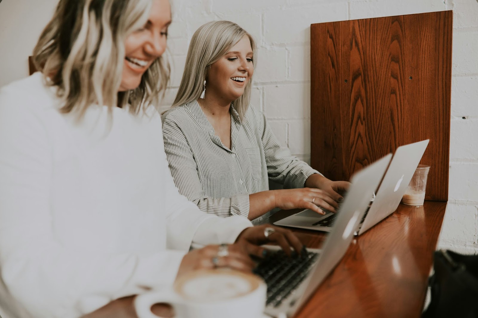 Two women working together at a table, each focused on their laptops, sharing ideas and collaborating on a project.